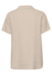 Chemise en lin beige avec col, manches courtes et coupe ample. Le tissu présente une texture naturelle et un ourlet droit en bas.