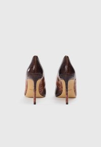 Brown high-heeled pumps with a textured leather upper, pointed toe, and thin stiletto heel. Interior features brand logo embossed on the sole.