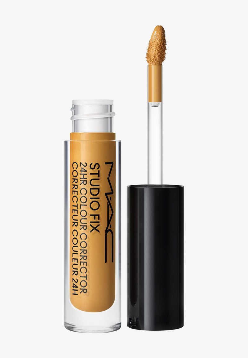 Correcteur liquide MAC Studio Fix longue tenue 24 heures avec bouchon noir et applicateur, montrant du correcteur beige sur la pointe.