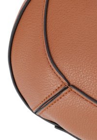 Brauner Lederball mit strukturierten Oberflächen. Mit schwarzen Akzenten entlang der Nähte, die seine runde Form und die Details der Nähte betonen.