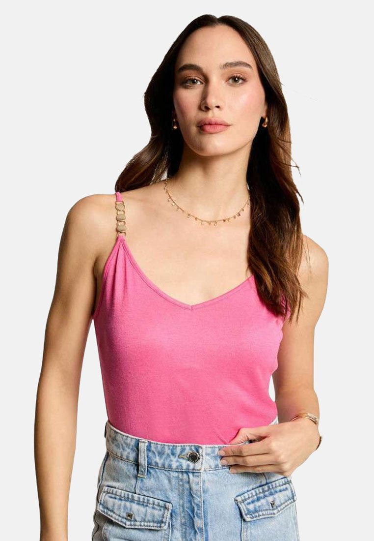 Haut sans manches rose avec un décolleté en V, doté de bretelles décoratives. Porté avec un short en denim taille haute bleu clair.