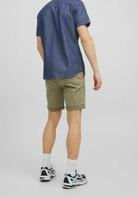 Džínová košile s krátkým rukávem v tmavě modré barvě spojená s olivově zelenými kraťasy. Bílé ponožky a sportovní boty s námořnickými a světle modrými akcenty.