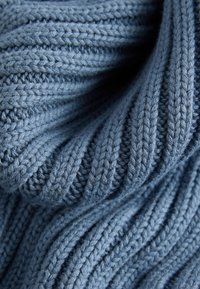Tissu tricoté bleu doux avec un motif côtelé montrant une texture détaillée et des plis diagonaux.