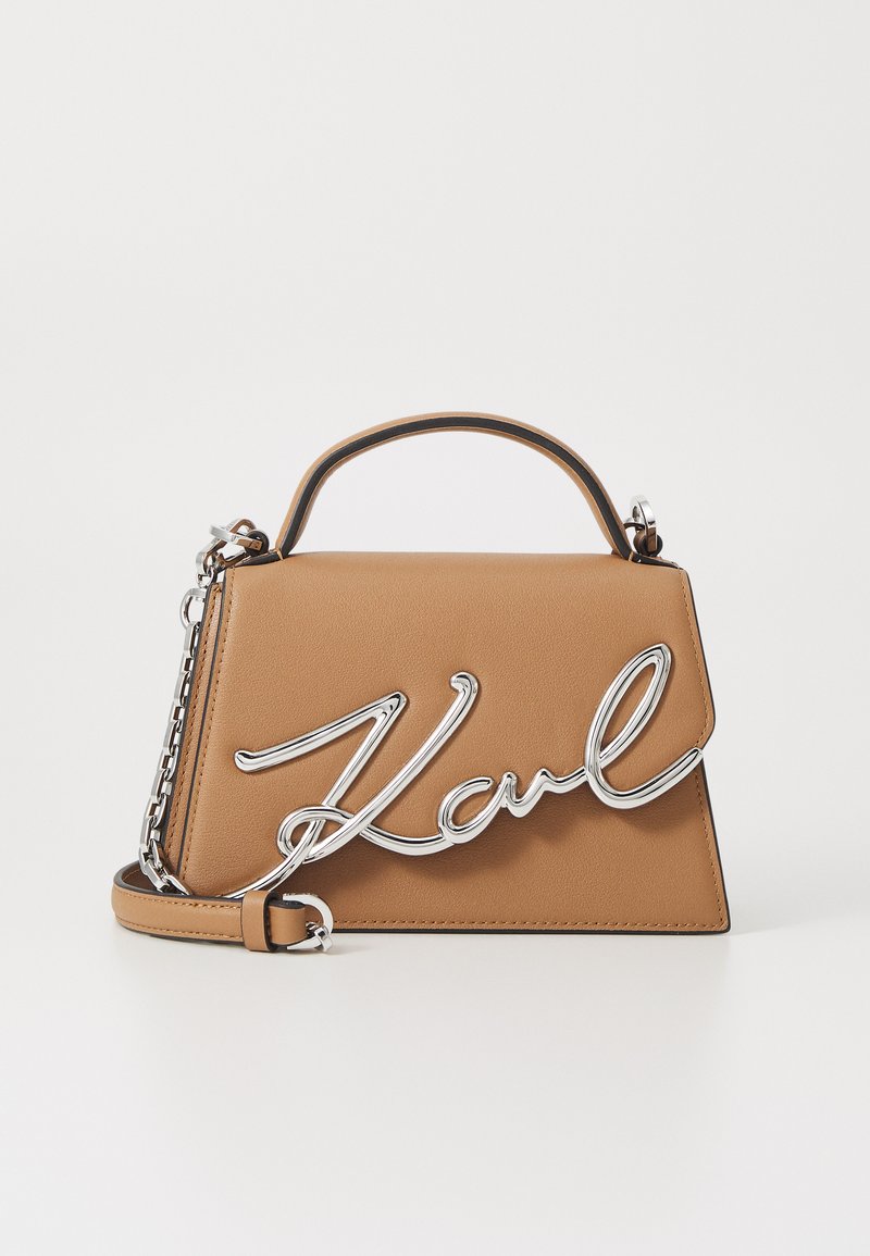 Tan-värinen nahkalaukku, jossa on jämäkkä muotoilu, yläkahva ja hopeinen "Karl"-logoyksityiskohta. Mukana irrotettava ketjuolkaimet.