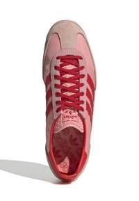 Rózsaszín sportcipő piros részletekkel, velúr és textil felsőrész, három piros csík, kerek orr, piros fűzők, mintás talpbetét, gumitalp.