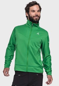 Grüner Reißverschlussjacke mit hohem Kragen, strukturiertem Stoff und zwei Seitentaschen. Mit einem stilisierten Logo auf der Brust.