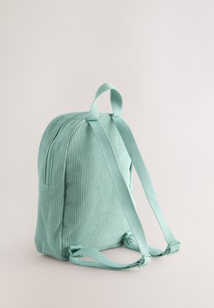 Velveta mugursoma mintzaļā krāsā ar polsterētām plecu siksnām, augšējo rokturi un sānu kabatu. Raksturota ar reljefu ribotu virsmu.