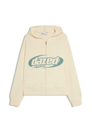 Krém színű cipzáras pulóver elöl zsebbel és kékeszöld "dazed HEARTS" logóval a mellkas közepén, fehér háttéren bemutatva.