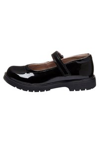 Black patent leather Mary Jane shoe with thick rubber sole and single Velcro strap, shown from the side on a white background.