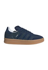 Sneaker blu scuro con tomaia in suede e denim, caratterizzato da tre strisce bianche, una linguetta imbottita e una suola in gomma con battistrada testurizzato.
