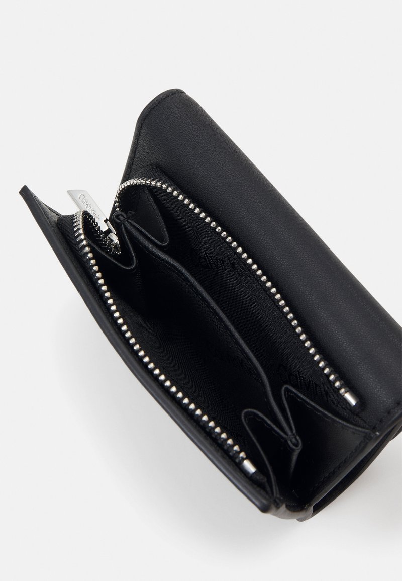 Schwarze Lederbörse mit glatter Textur, Reißverschluss, mehreren Fächern und hardware in Silberoptik. Das Innere zeigt einen Logo-Druck.