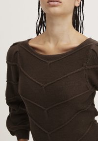 Brown knitted sweater with a textured zigzag pattern, wide neckline, and fitted sleeves. Made of a soft material with visible stitching details.