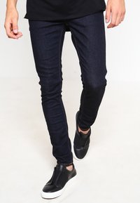 Mörkblå skinny jeans i denim, med slim fit, kontrastsöm och matchade med svarta slip-on skor.