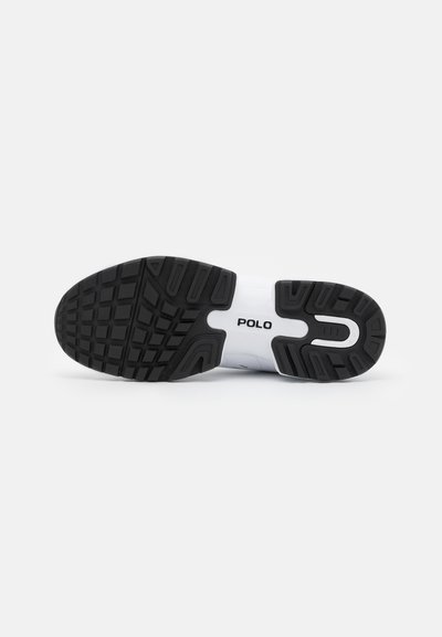 Suela de zapatilla deportiva, goma negra con un patrón de agarre texturizado. La entresuela blanca presenta la marca "POLO" en negro.