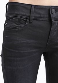 Svarta denimjeans har en smal passform, fem fickor, en subtil textur och en knappstängning med detaljer i metall.