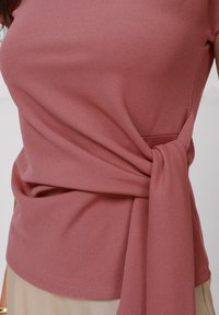 Krátky rukáv top v prašnej ružovej farbe so šnúrovacím detailom na boku. Mäkká, elastická tkanina s hladkou textúrou a priliehavým strihom.