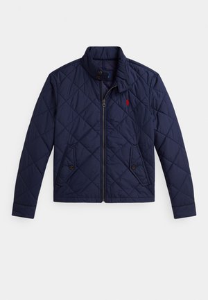 Tumši zila šūta jaka ar priekšējo rāvējslēdzēju, divām kabatām ar pogām, stāvošu apkakli un sarkanu izšūtu logotipu kreisajā krūtī.