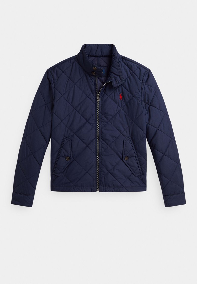 Tumši zila šūta jaka ar priekšējo rāvējslēdzēju, divām kabatām ar pogām, stāvošu apkakli un sarkanu izšūtu logotipu kreisajā krūtī.