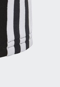 Shorts atletici a strisce bianche e nere, realizzati con un tessuto morbido e con cuciture visibili lungo le cuciture.