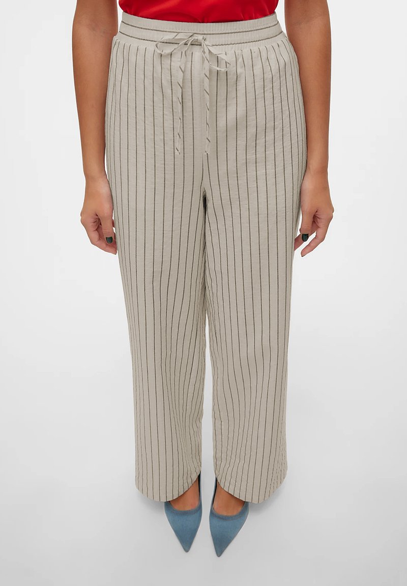 Lys beige, stripete vide bukser med strikket midje. Tøyet har en myk tekstur. Kombinert med lyseblå spisse hæler.