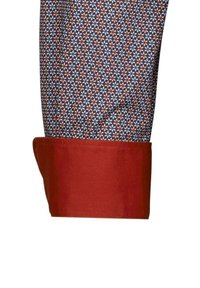 Tessuto multicolore con motivi floreali in blu navy, rosso e bianco; presenta un polsino rosso arrotolato.