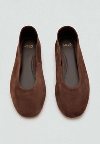 Een paar bruine suède balletschoenen met ronde neuzen en het "MNG"-logo op de gevoerde binnenzolen, weergegeven op een lichte achtergrond.