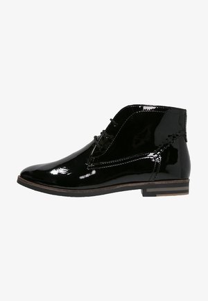 Botines de charol negro con un diseño elegante, puntera redondeada, cierre con cordones y un tacón bajo apilado. Presenta detalles de costura.