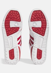 Zapatillas Adidas rojo y blancas con suelas de goma texturizadas, con tres franjas rojas y logotipo de la marca en relieve en los laterales.