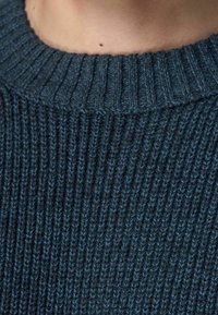 Sweter wełniany w ciemnym teal z prążkowaną fakturą i dopasowanym dekoltem. Posiada gładki, miękki wygląd przędzy.
