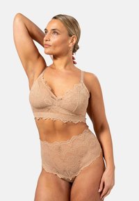 Beige pitsi bralette ja kõrge vöökohtadega aluspüksid, millel on lainelised ääred ja lillemustrid, reguleeritavad rihmad mugavuse tagamiseks.