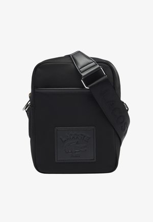 Schwarze synthetische Umhängetasche mit glatter Struktur, mit einem gut sichtbaren geprägten Logopatch und einem breiten verstellbaren Riemen.