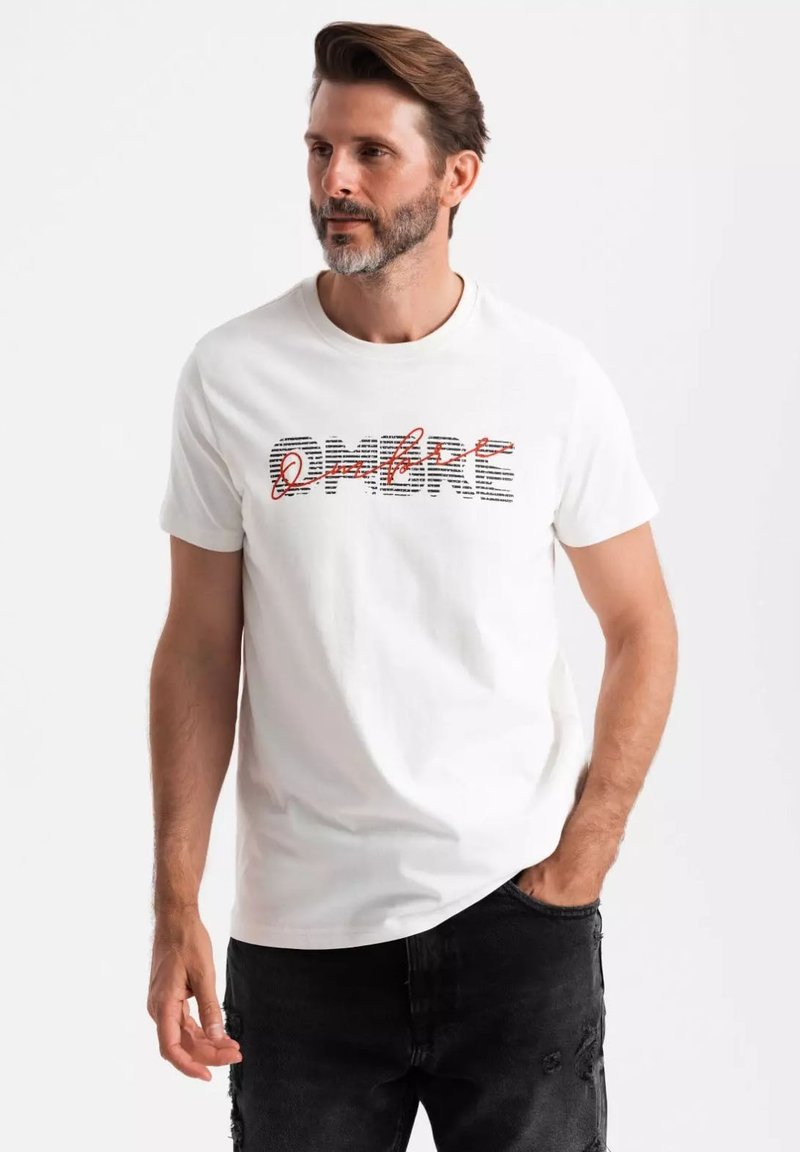 Camiseta de algodón blanca con un gráfico audaz "OMRE" en texto a rayas negro y rojo. Cuello redondo, mangas cortas y corte relajado.