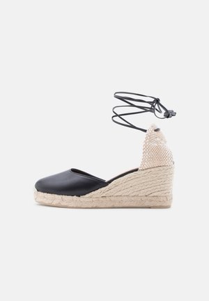 Svart espadrille kilehæl med flettet jutesåle, beige vevd hæl og svarte ankelbånd med dekorative blomsterender.