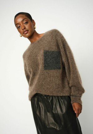 Brown fuzzy sweater with a dark gray square pocket, paired with a black leather skirt. Overall relaxed fit and textured fabric.