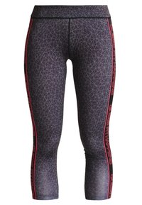 Svarta capri leggings med ett geometriskt mönster, röda sidostrålar med texten "Guess Fit Happens" och ett mjukt, elastiskt tyg.