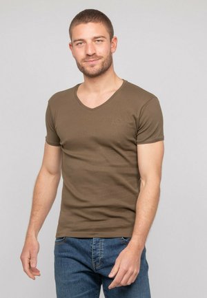 T-shirt vert olive à col en V avec manches courtes, fabriqué dans un tissu lisse. Présente un logo discret brodé sur la poitrine. Design ajusté.