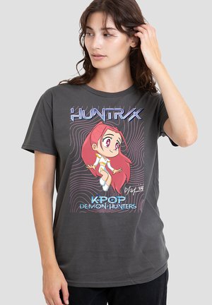 Gray cotton t-shirt featuring a pink-haired cartoon character with large eyes, surrounded by stylized text "HUNTRX KPOP DEMON HUNTERS."