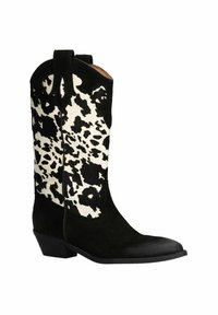 Bottes de cowboy en daim noir avec un insert en cuir noir et blanc à pois, bout pointu et talon bas empilé. Comprend des languettes pour un enfilage facile.