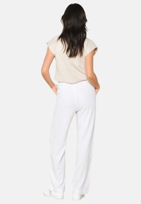 Beige short-sleeve top with a relaxed fit paired with white wide-leg pants. Smooth fabric, minimal seams, and a soft texture.