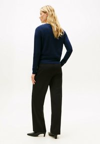 Suéter de marinero de manga larga, escote redondo, con dobladillo acanalado. Pantalones negros ajustados, pierna recta, textura suave. Tacones negros puntiagudos.