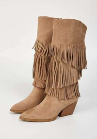 Bottes à talons en daim marron avec un design à bout pointu, présentant des franges superposées le long de la tige supérieure pour un aspect texturé.