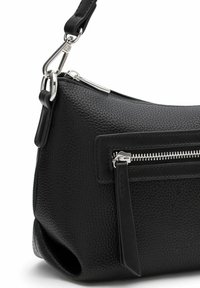 Zwarte gestructureerde leren handtas met een ritsvak en elegante zilveren accenten. Voorzien van een verstelbare strap en een kenmerkende platte bodemvorm.