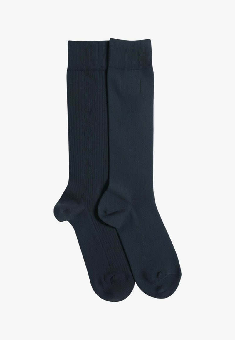 Calcetines azul marino, uno con textura acanalada y detalle de logo, el otro liso. Ambos hasta la rodilla con puntera y talón reforzados para mayor durabilidad.