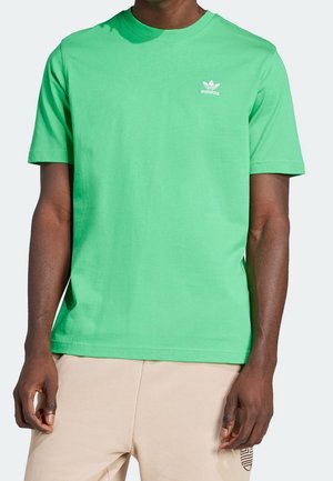 Grøn bomulds-T-shirt med rund hals. Har hvidt "adidas" logo og ikonisk trefoil på venstre bryst. Korte ærmer og afslappet pasform.
