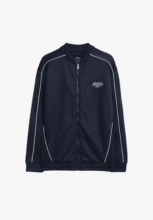 Veste zippée marine en tissu doux avec des bordures blanches contrastées. Dotée d'un col montant et de poches à l'avant. Logo "1989 Hudson Baseball Dept NYC" sur la poitrine.