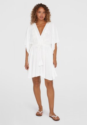 White short dress with a deep V-neck, loose sleeves, and a drawstring waist. Features a textured fabric and decorative tassels.