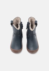 Mørkeblå lærstøvler med en myk beige fôr, rund tå og ribbet gumm såle. To sidelukninger og en bakre pull-tab for enkel påkledning.