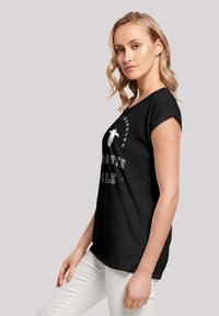 Schwarzes T-Shirt mit kurzen Ärmeln, mit weißem grafischem Text "SÜDPOLE" und Pinguin-Design. Weicher Stoff, lockere Passform, abgerundeter Saum.