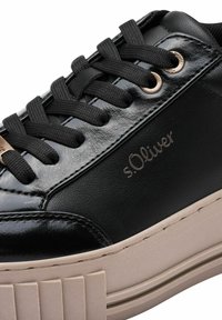 Sneaker din piele întinsă neagră cu șireturi negre, având un toc texturat, talpă platformă bej și un branding subtil pe lateral.