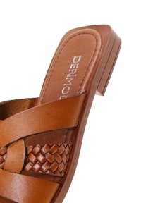 Infradito in pelle marrone con dettaglio della fascia intrecciata, suola piatta, punta rotonda e logo impresso sulla soletta.